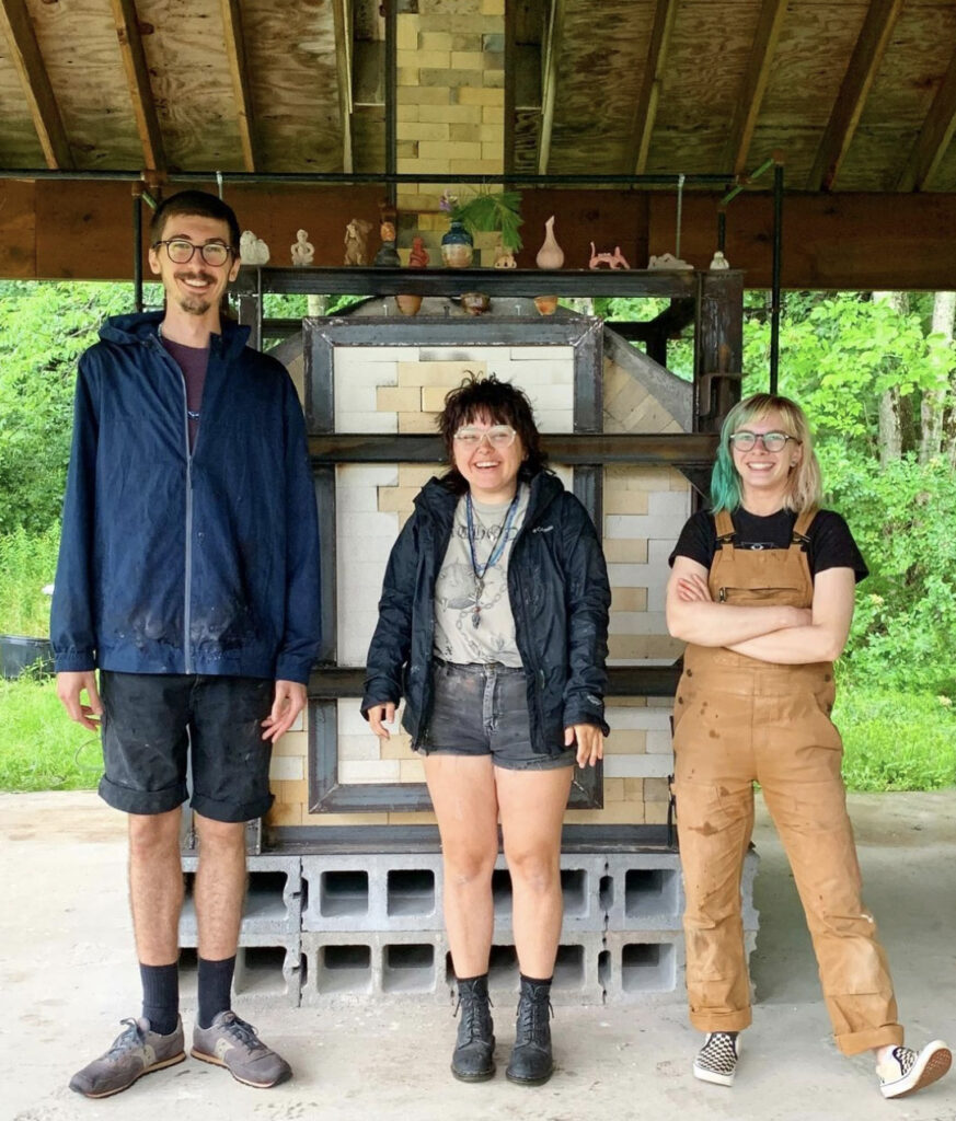 Three people standing in front of a kiln outsidee