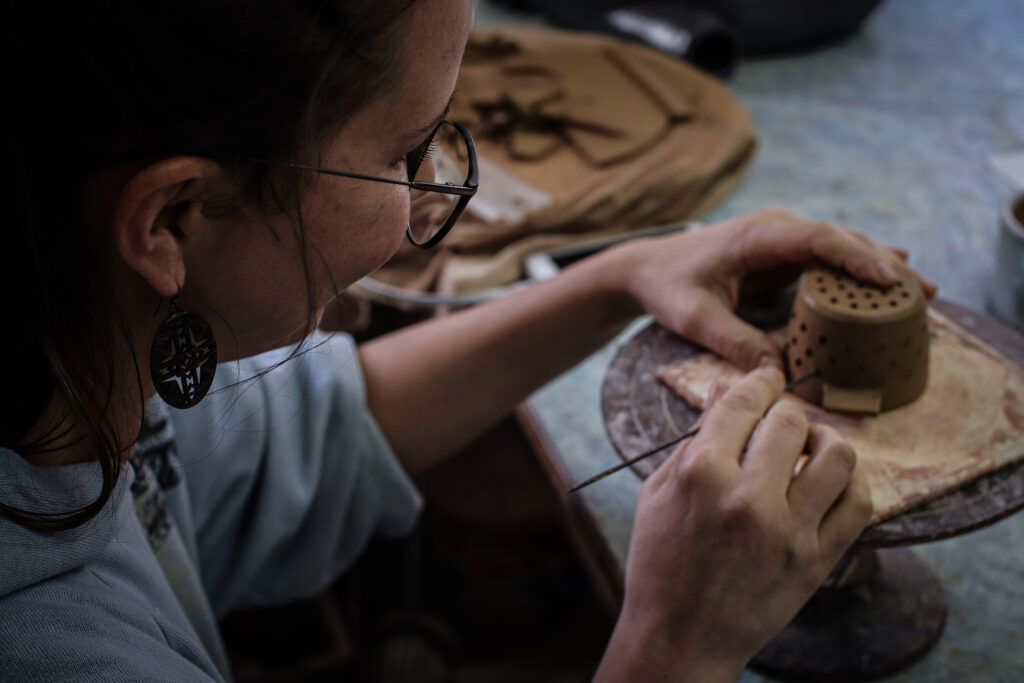 Young person decorating pottery