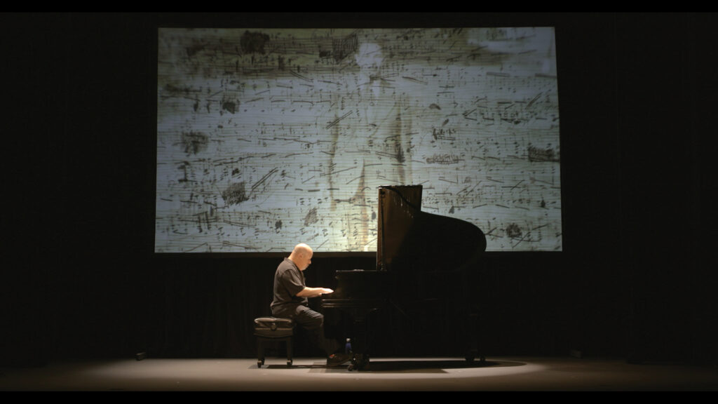 Man seated at piano on stage