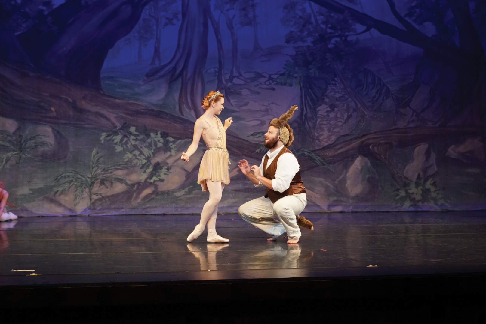 Man kneeling before a woman on stage.