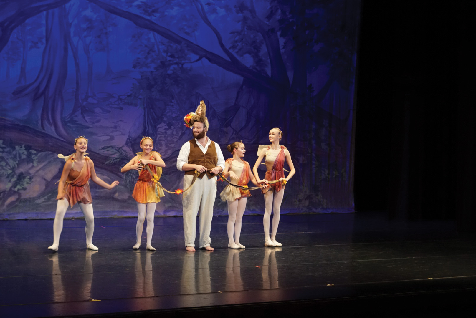 Four dancers surround actor on stage