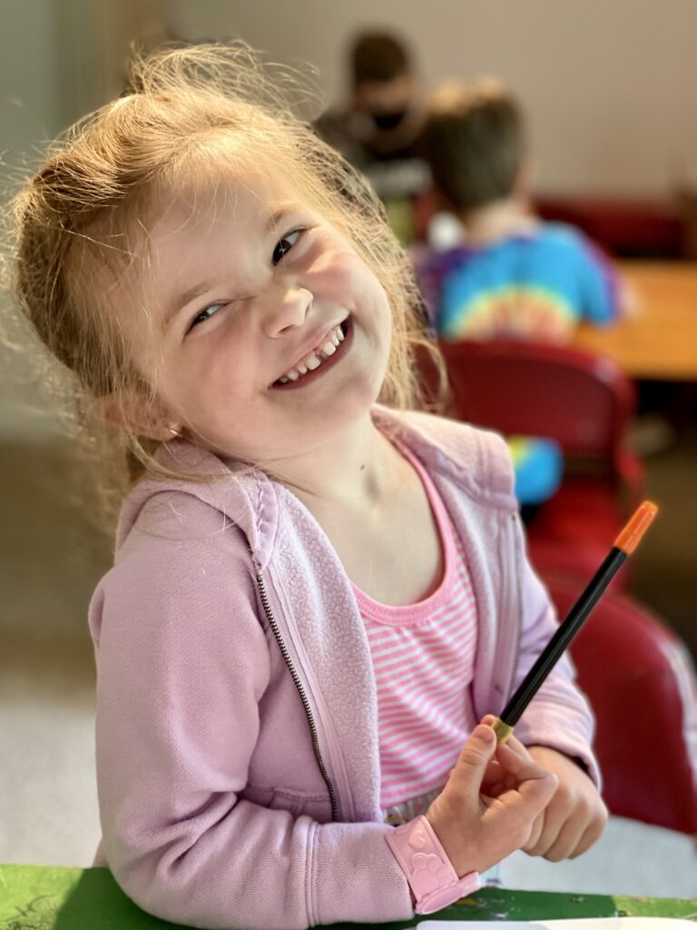 little girl smiling with paint brush