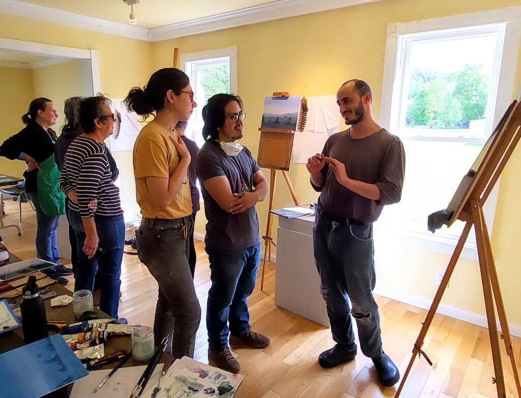 Group of people in a gallery stand in front of easels