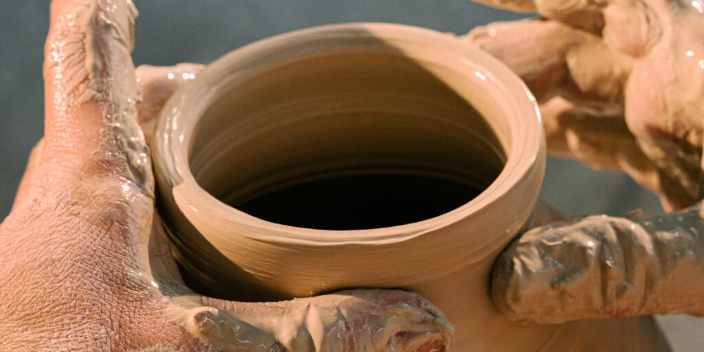 Hands shaping pot on potter's wheel