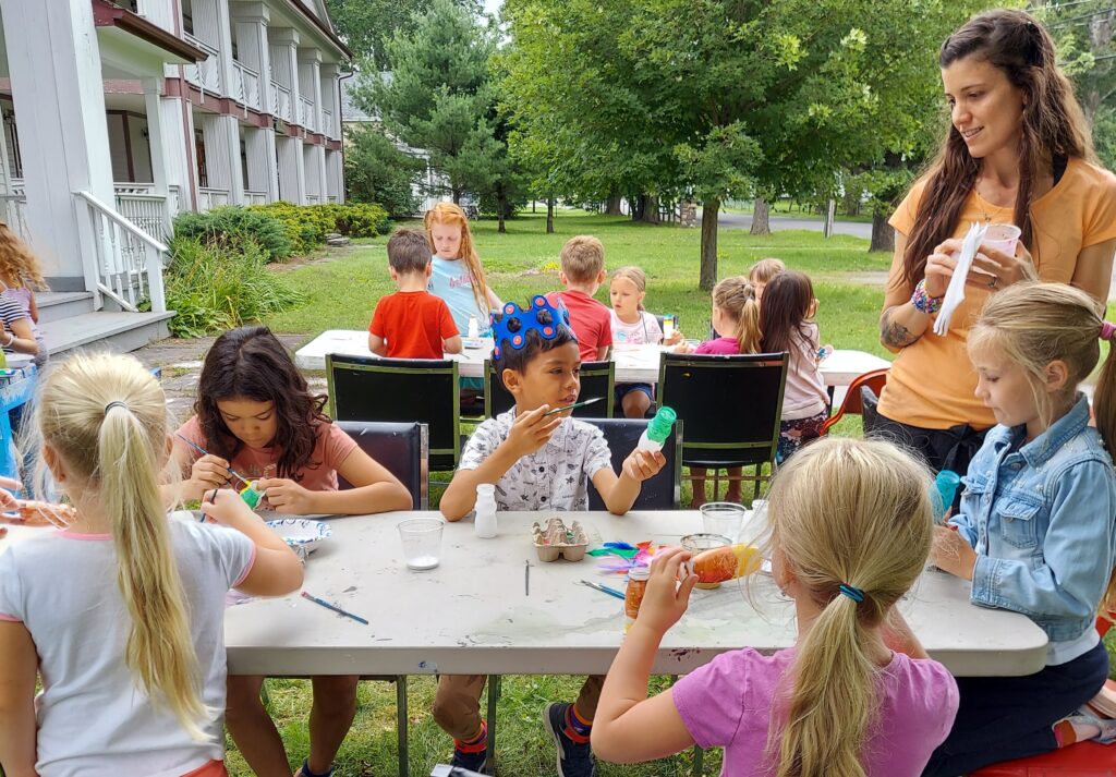 Children make crafts at a table outside