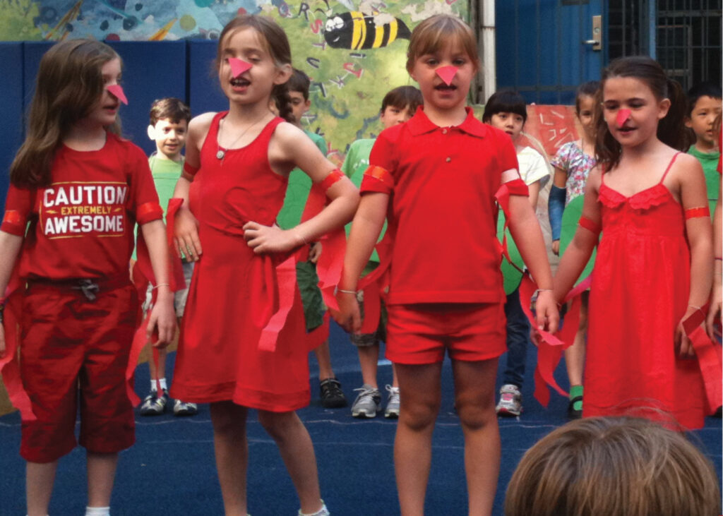 Group of children dressed in red perform on stage.