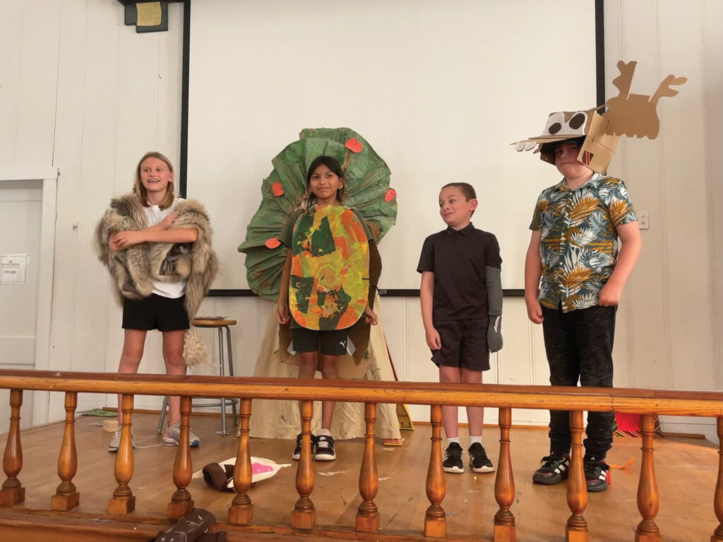 Four children in costume perform on stage