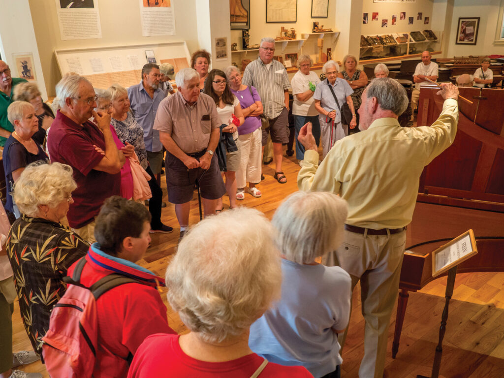 A group of seniors listen to a tour of the Piano Museum