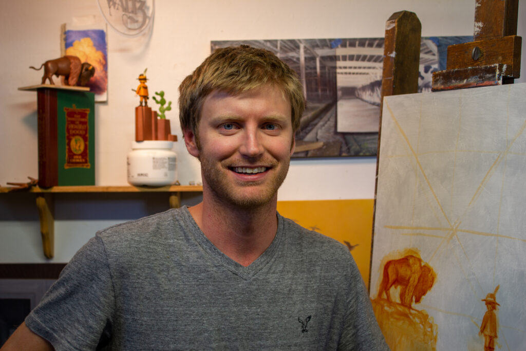 Artist Nathan Loda stands in front of an easel in his studio
