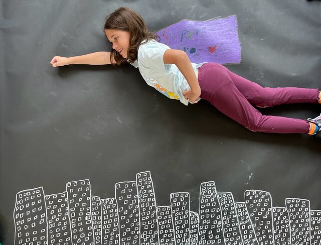 Girl in cape posing over image of city