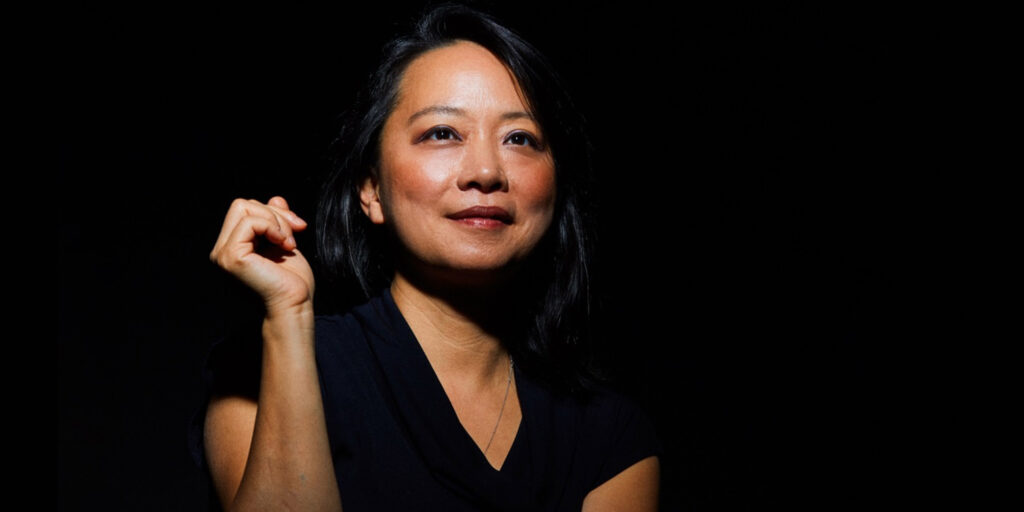 Woman poses against black background