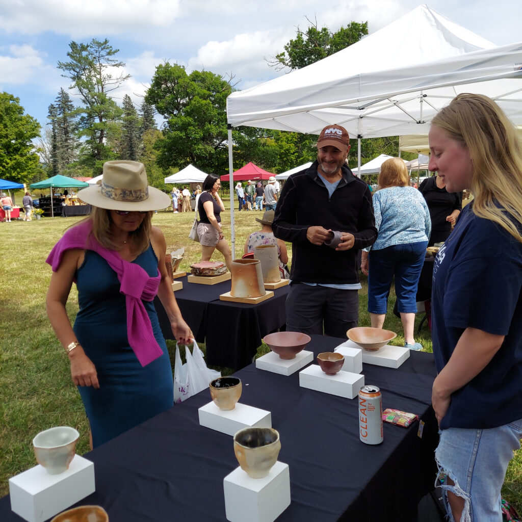 Group of people stand at a table with pottery.