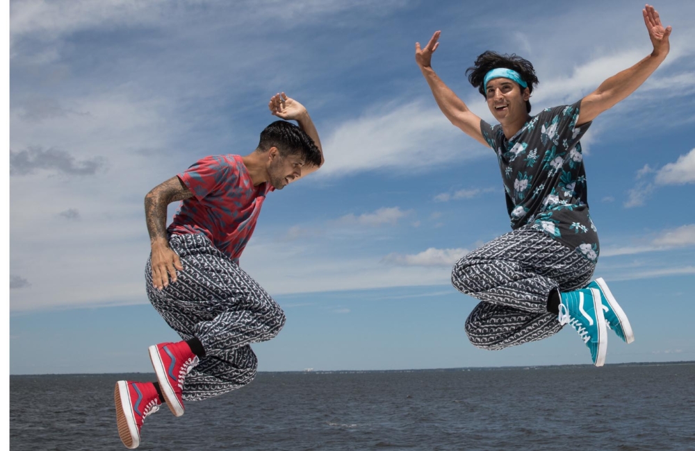 Two men leaping in the air in front of the ocean.