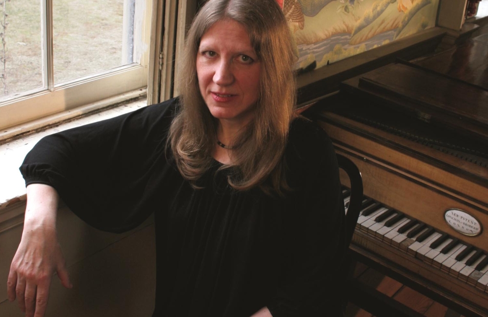 woman seated in front of piano at window