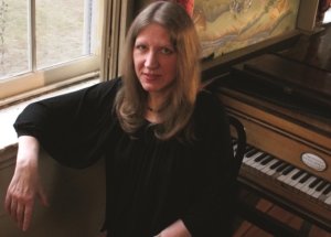 woman seated in front of piano at window