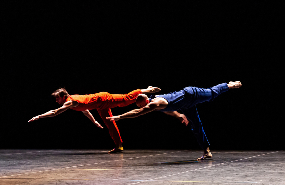 Two dancers on stage against a black background