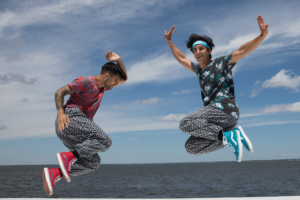 Two men leaping on stage in front of ocean