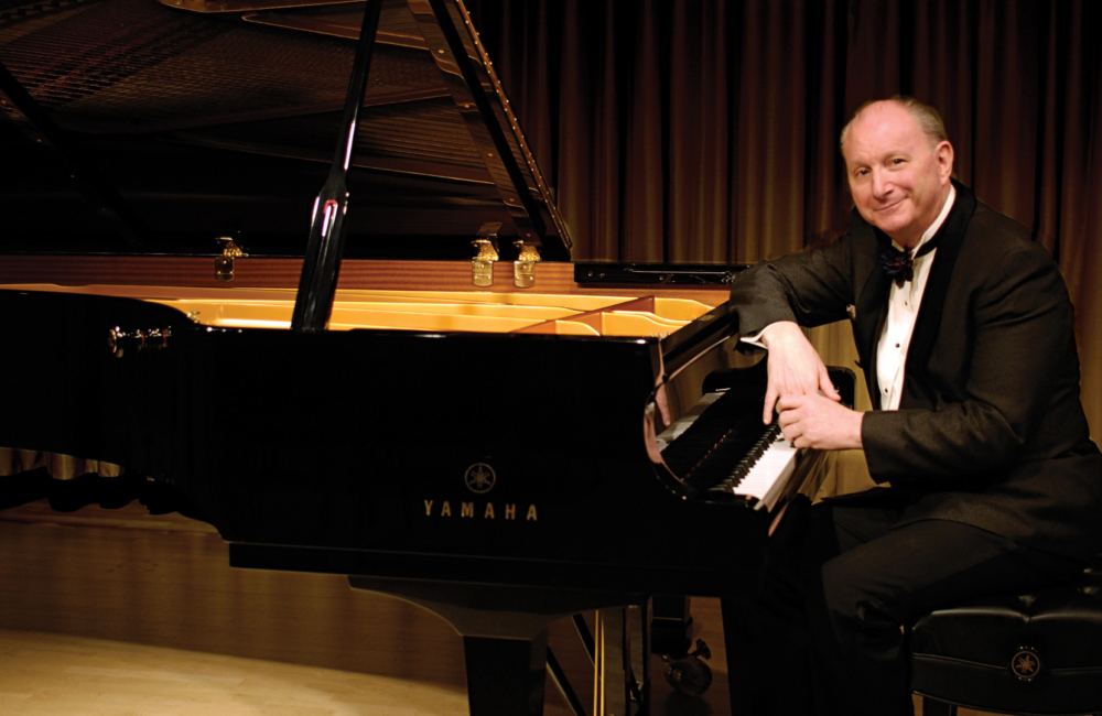 Man in tuxedo sits at a grand piano